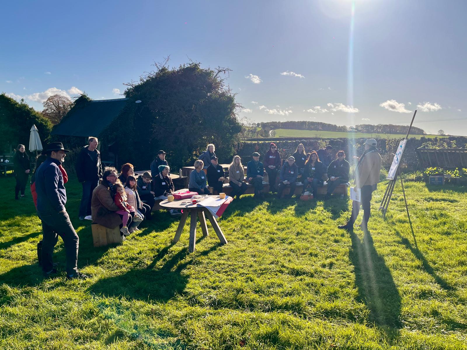 A group of people gather around on a sunny day in the countryside.