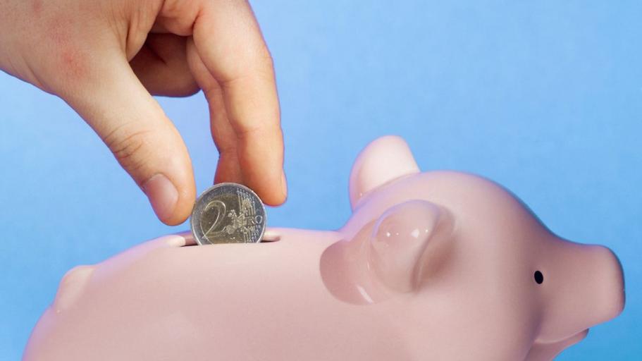 Photo of someone putting money into a piggy bank