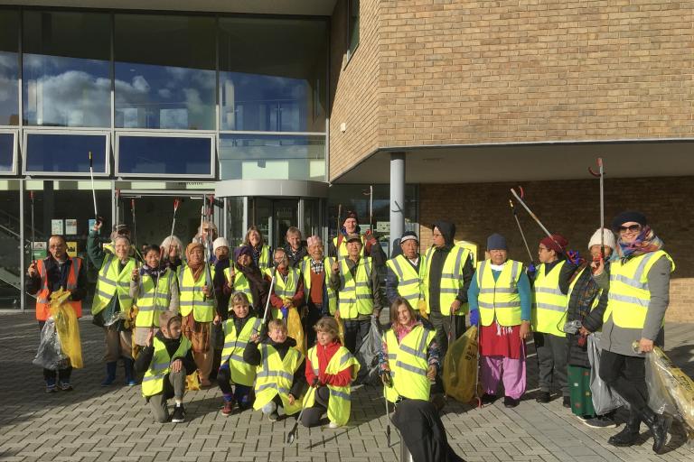 A large group of litter pickers with high-vis vests and rubbish grabbers