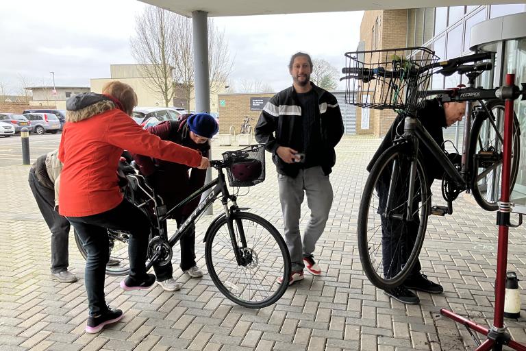 Four people working on repairing a bike