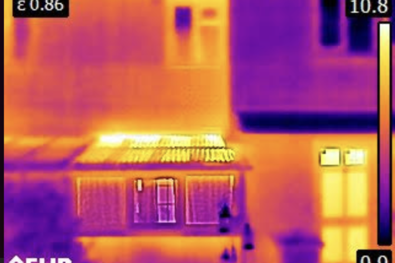 A thermal image of a house with areas such as windows showing lots of heat leakage