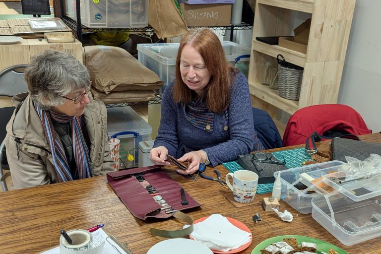 Two people discussing leatherworking tools