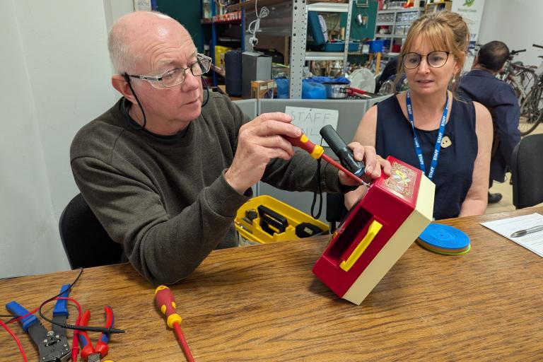 A man and a woman repairing a record player