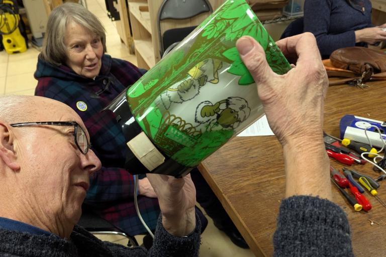 A man investigating a green womble lamp to see where it is broken