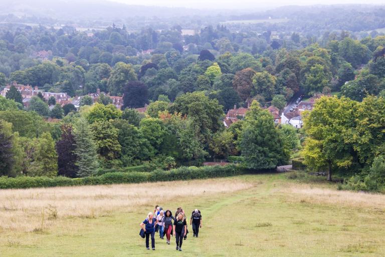 A small group of people stand far away in the picture in a large, open field, walking towards the camera.