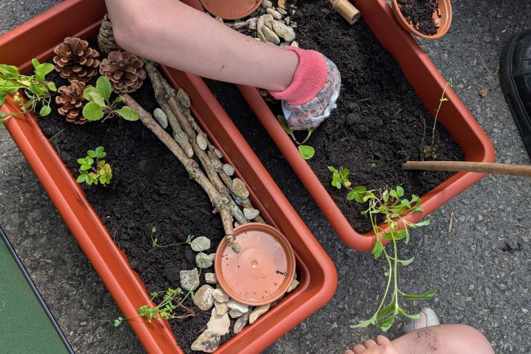 People wearing gardening gloves work on some planters.