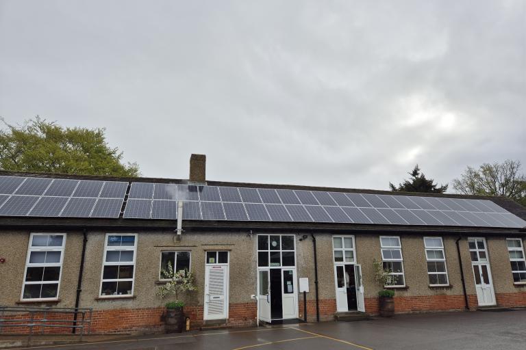 A single-story classroom building with solar panels stretched along the entire length of the roof.