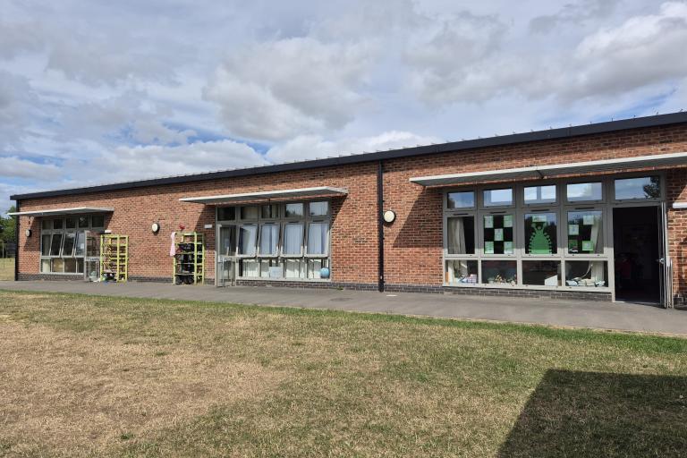 A single-story school building with overhanging shades installed above all of its windows and doors.