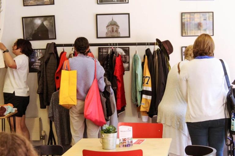 Four women browse a second-hand clothes rack.