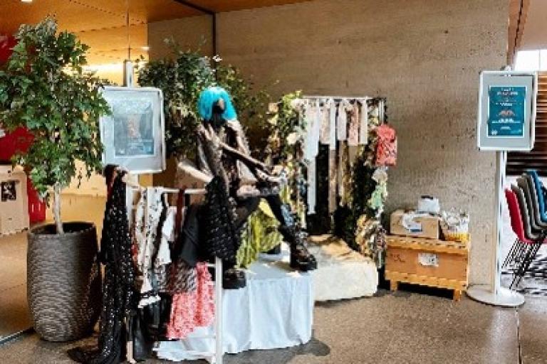 A collection of clothes on racks and mannequins sits on display.